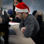 A man wearing a santa hat sitting at a desk